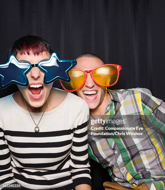 couple in photo booth wearing oversized sunglasses - photo strip stock pictures, royalty-free photos & images