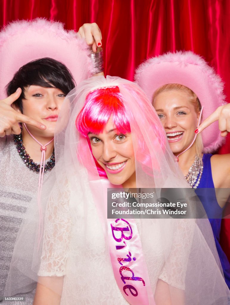 Women in photo booth, one wearing bridal veil