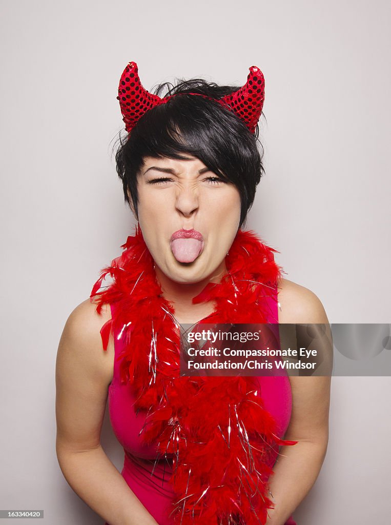 Woman wearing devil costume sticking out tongue