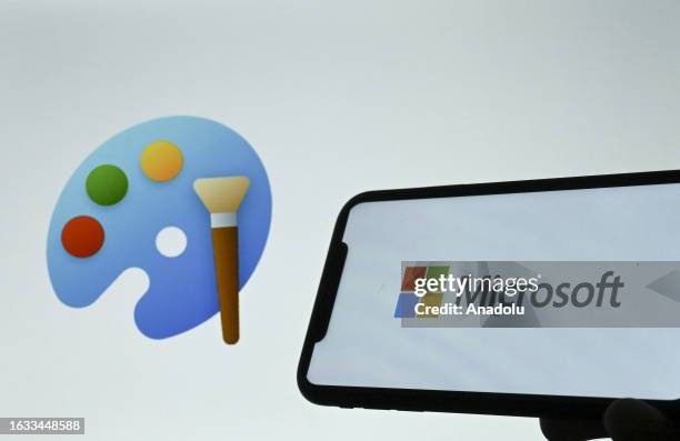 The logo of Microsoft is displayed on a mobile phone screen in front of a computer screen displaying the logo of Paint in Ankara, Turkiye on August...