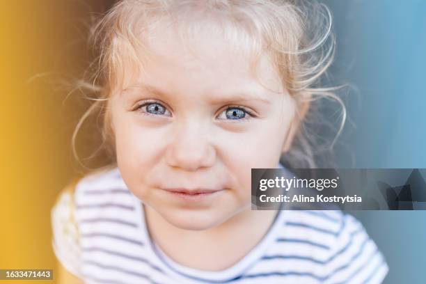 portrait of beautiful child on blue-yellow background - baby blue eyes stock pictures, royalty-free photos & images