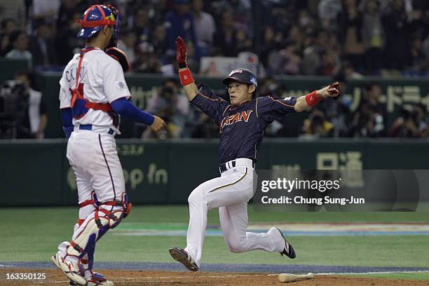 Yuichi Honda of Japan slides into home base to score in the eighth inning during the World Baseball Classic Second Round Pool 1 game between Japan...