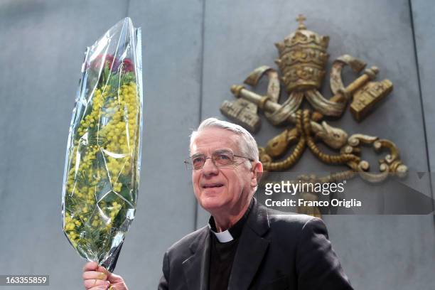 Vatican spokesman father Federico Lombardi holds a bunch of mimosa, a flower marking the International Women's Day on March 8, as he arrives at the...