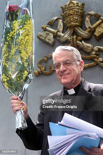 Vatican spokesman father Federico Lombardi holds a bunch of mimosa, a flower marking the International Women's Day on March 8, as he arrives at the...