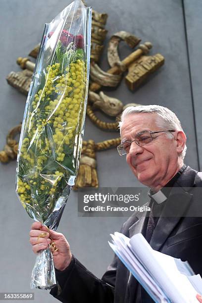 Vatican spokesman father Federico Lombardi holds a bunch of mimosa, a flower marking the International Women's Day on March 8, as he arrives at the...