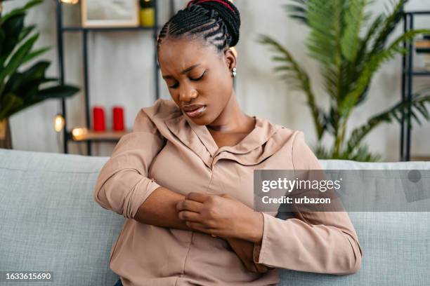 young woman scratching her skin at home - eczema stock pictures, royalty-free photos & images