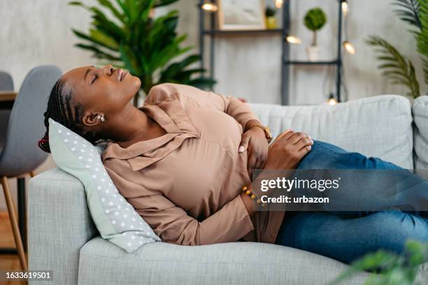 young woman having period cramps at home - irritable bowel syndrome stock pictures, royalty-free photos & images