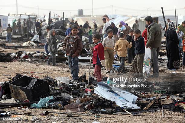 Children walk among the remains of a fire which broke out in Al Zaatari camp for Syrian refugees on March 8, 2013 in Zaatari, Jordan. No refugees...