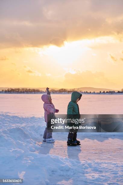 a child learns to skate on a makeshift ice rink on the lake. - figure skating child stock pictures, royalty-free photos & images