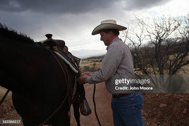 Cattle rancher Dan Bell adjusts his saddle while riding at his ZZ Cattle Ranch along the U.S.-Mexico border on March 8, 2013 in Nogales, Arizona....