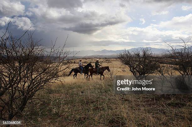 Border Patrol ranch liaison John "Cody" Jackson and cattle rancher Dan Bell ride through Bell's ZZ Cattle Ranch along the U.S.-Mexico border on March...