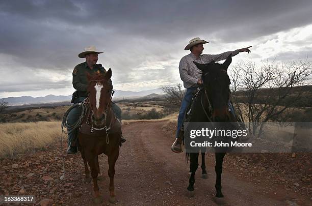 Cattle rancher Dan Bell points toward a group of people walking along the Mexican side of the U.S.-Mexico border fence on March 8, 2013 in Nogales,...