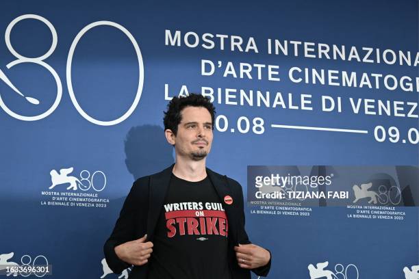 Director and president of the jury Damien Chazelle wearing a tee-shirt in solidarity with Writers Guild on strike poses on August 30 during a...