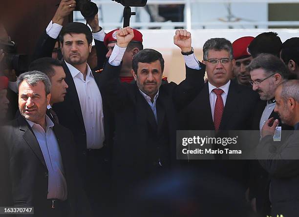 Iranian President Mahmoud Ahmadinejad raises his hands toward cheering supporters while standing next to Venezuela's Foreign Minister Elias Jaua as...