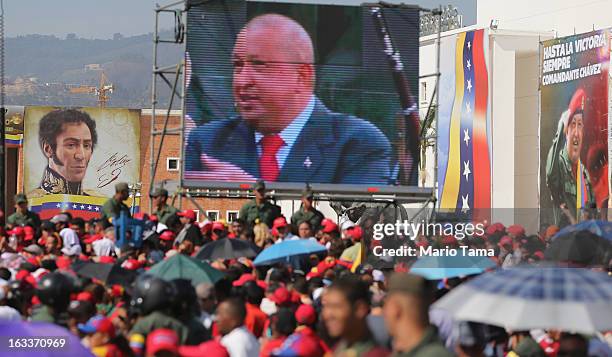 People gather to watch a live broadcast of the funeral for Venezuelan President Hugo Chavez as a video of Chavez is played outside the Military...