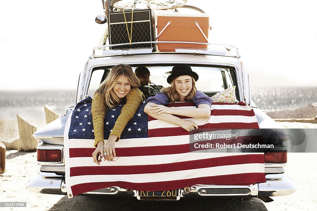 Two girls smiling from the back of a car.