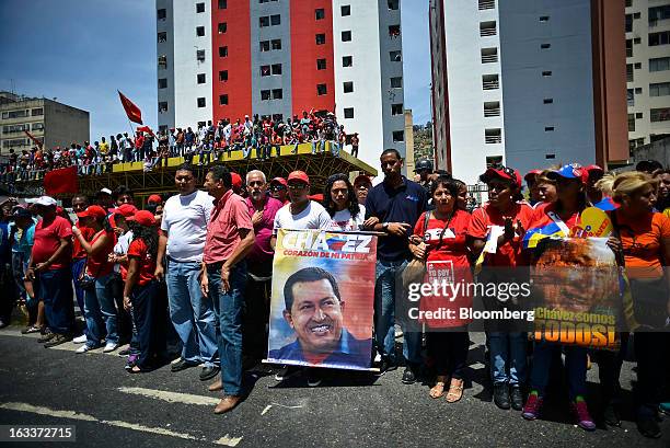 Supporters hold posters while gathering to pay their respects during the funeral for Venezuelan President Hugo Chavez in Caracas, Venezuela, on...