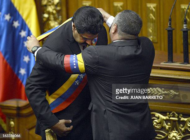 The President of the National Assembly, Diosdado Cabello puts the presidential sash on Venezuelan Vice President Nicolas Maduro after he was sworn in...