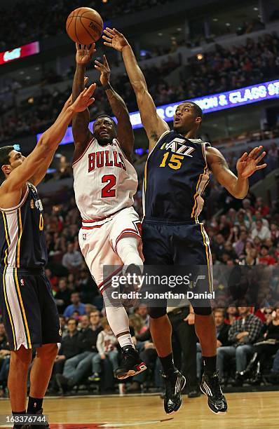Nate Robinson of the Chicago Bulls goes up for a shot between Enes Kanter and Derrick Favors of the Utah Jazz at the United Center on March 8, 2013...