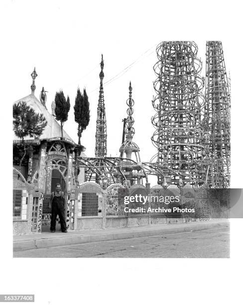 Italian-born architect Simon Rodia standing outside his Watts Towers, a monument of steel, concrete, and found materials, which he constructed by...