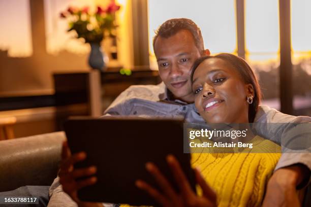 couple watching a movie together on their sofa - serviço de distribuição digital contínua imagens e fotografias de stock