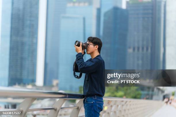 a tourist man walking with a camera along marina bay. singapore - east asian works of art specialist stock pictures, royalty-free photos & images