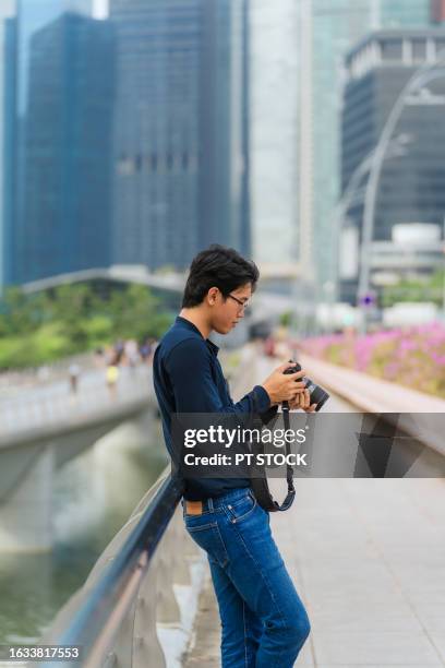 a tourist man walking with a camera along marina bay. singapore - east asian works of art specialist stock pictures, royalty-free photos & images