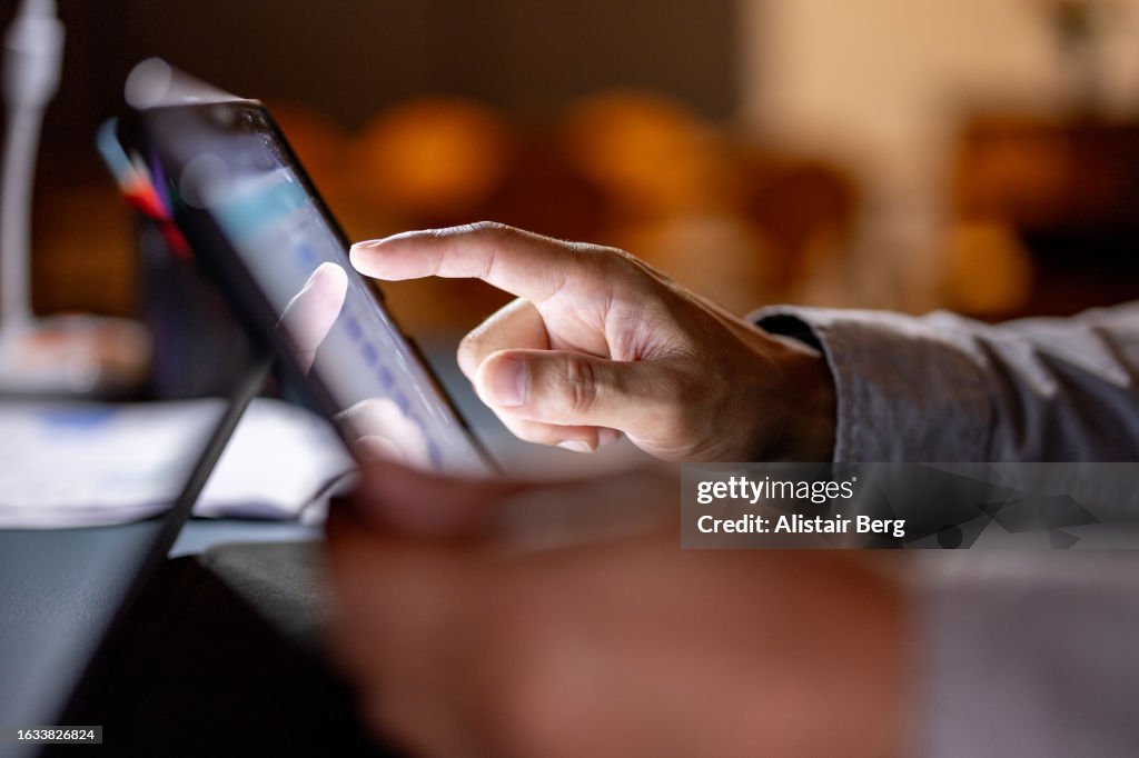 Close up hand scrolling on a digital tablet at night