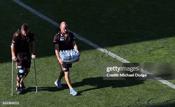Matthew Suckling of the Hawthorn Hawks walks to the bus on crutches with fitness coach Andrew Russell after sustaining a right leg injury during the...