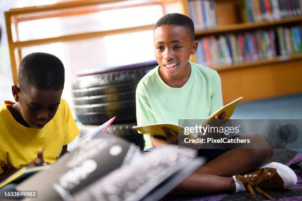 candid portrait young boy sitting in group reading together in library - boy library stock pictures, royalty-free photos & images