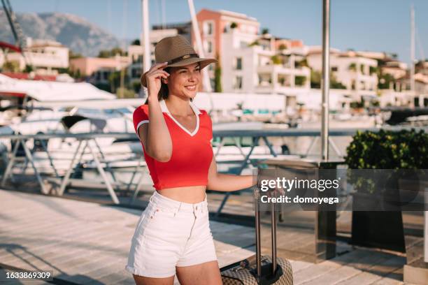 young woman with a suitcase at the seaport on a sunny summer day - summer woman stock pictures, royalty-free photos & images