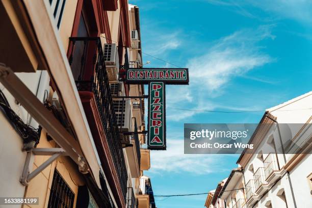 low angle view of shop sign of a restaurant hanging on the street - store sign stockfoto's en -beelden