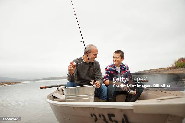 a day out at ashokan lake. a man and a boy sitting fishing from the boat. - ashokan reservoir stock pictures, royalty-free photos & images