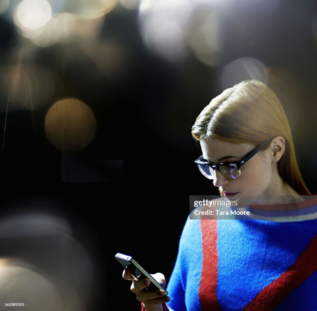 Woman texting on mobile phone with lens flare