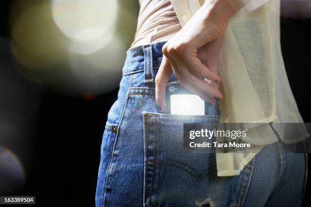 woman putting illuminated mobile into back pocket - hands in pockets foto e immagini stock