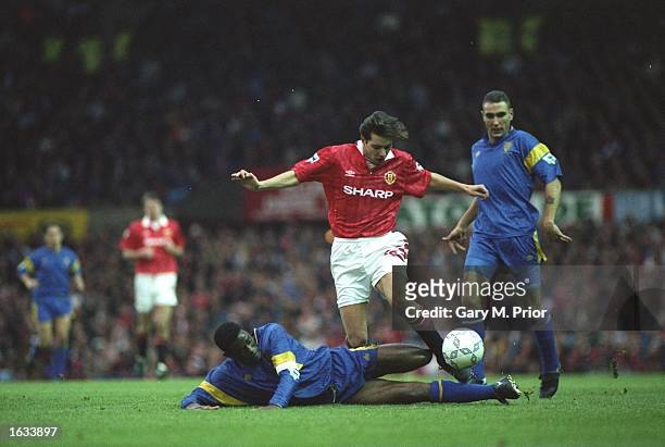 Robbie Earle of Wimbledon slides in to tackle Darren Ferguson of Manchester United during an FA Carling Premier League match at Old Trafford in...