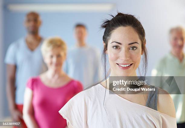 portrait of woman at front of community group - yoga pose photos et images de collection