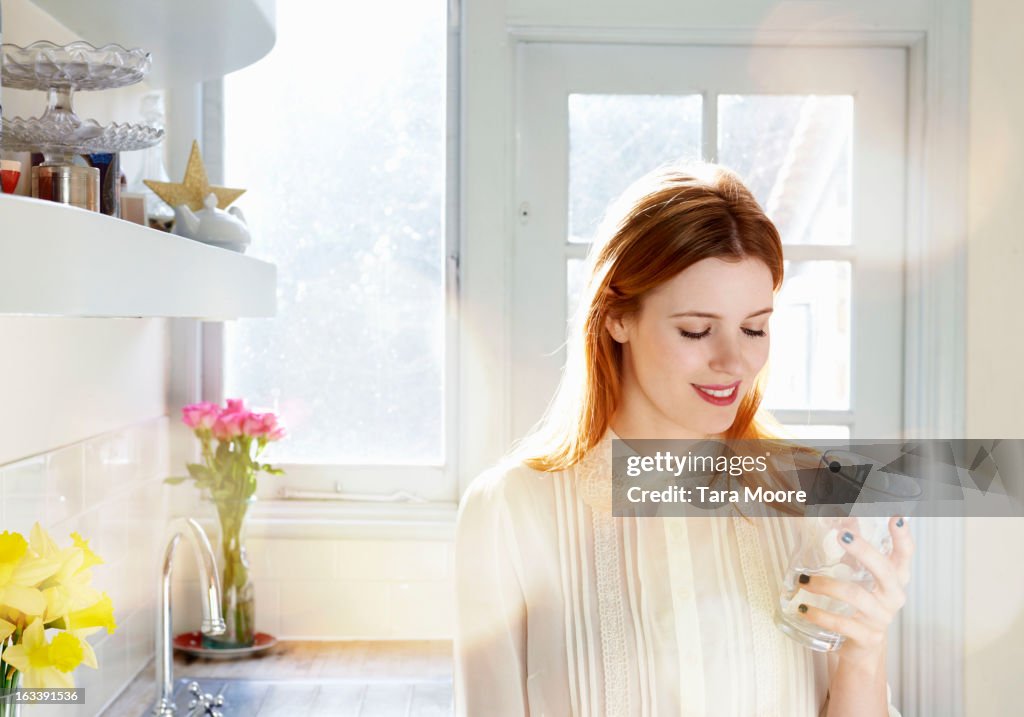 Woman smiling with glass of water in kitchen