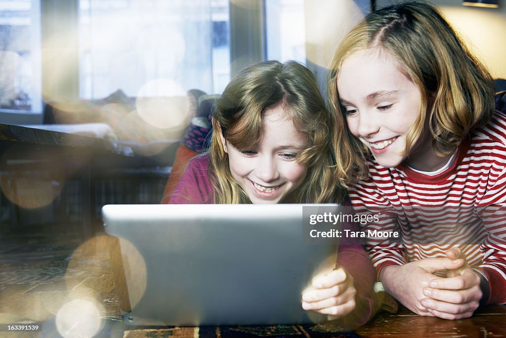 Two young girls playing with digital tablet