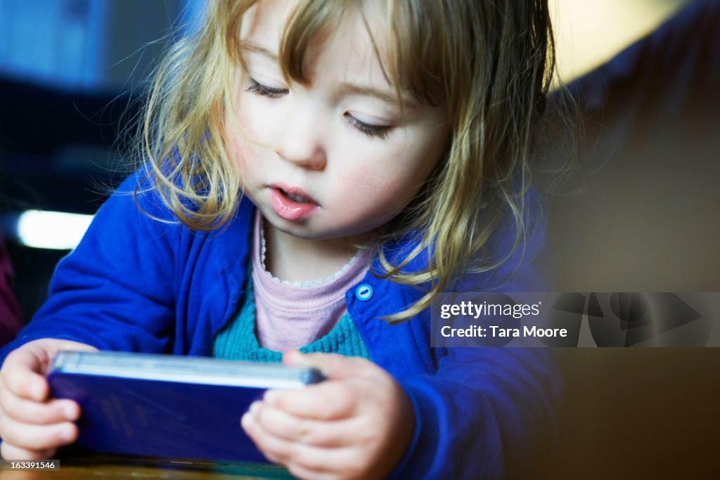 Young girl playing game on mobile phone