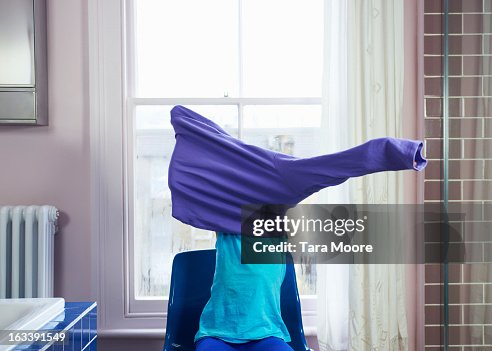 Child getting changed by putting on sweater Child getting changed by putting on sweater