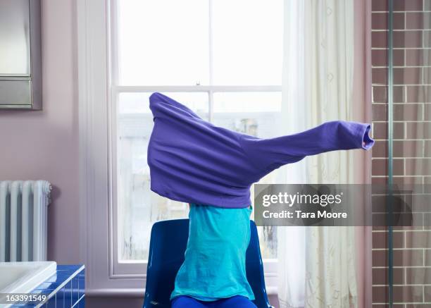 child getting changed by putting on sweater - aankleden stockfoto's en -beelden