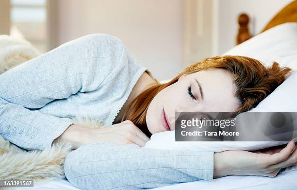 woman asleep in bed - women sleeping stockfoto's en -beelden