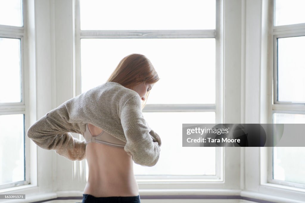 Woman getting dressed by window