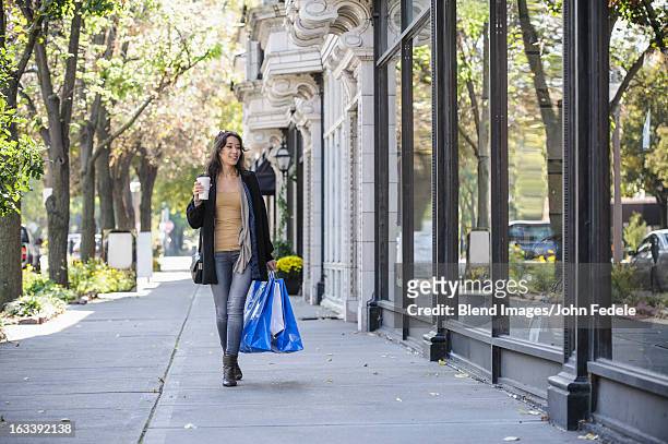 mixed race woman carrying shopping bags - woman carrying tote bag fotografías e imágenes de stock