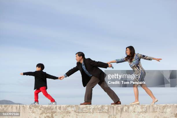chinese family holding hands and balancing on wall - child boy arms out stock pictures, royalty-free photos & images