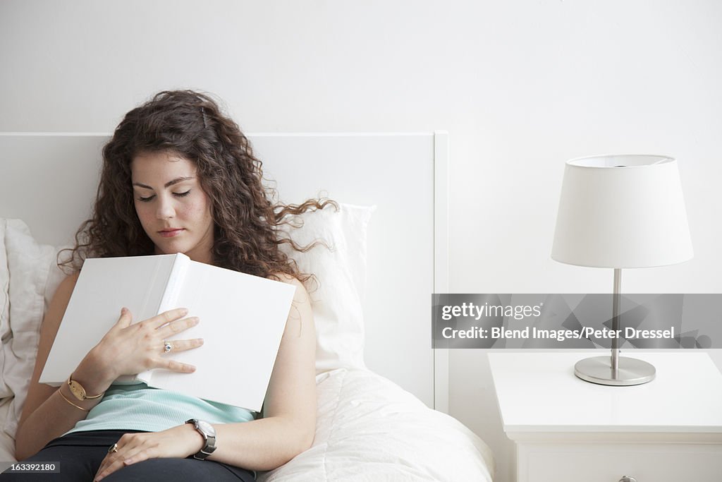 Caucasian woman sleeping in bed holding book