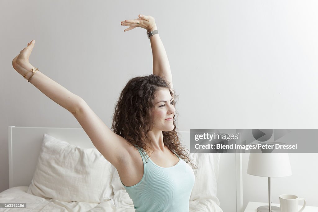 Caucasian woman stretching in bed