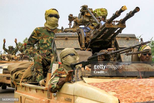 Fighters ride in a vehicle moving in a military convoy accompanying the governor of Sudan's Darfur State during a stopover in the eastern city of...