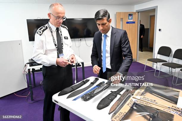 Britain's Prime Minister Rishi Sunak and Metropolitan Police Commissioner Mark Rowley look at knives and machetes seized from knife attacks during a...